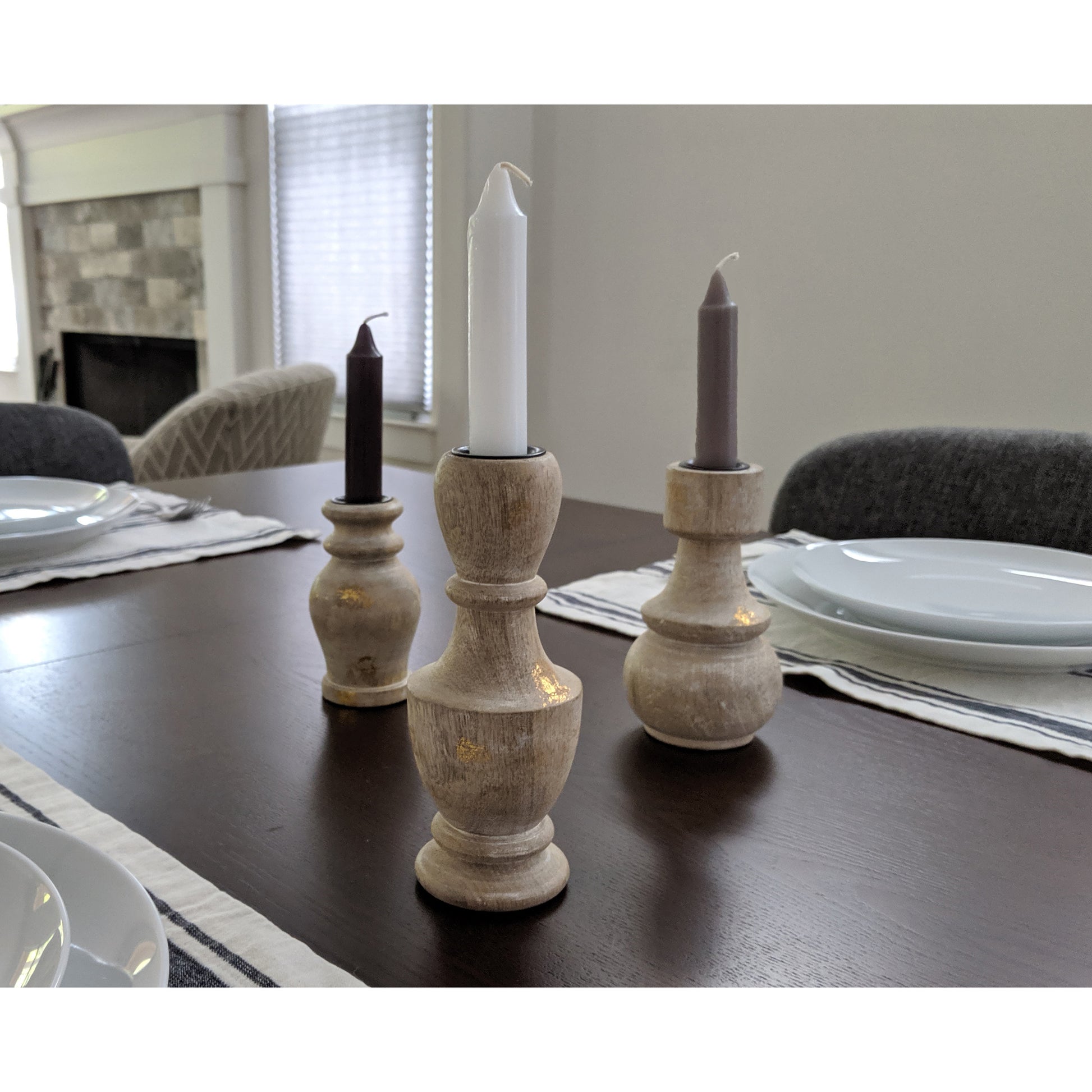 Image, white, grey and black candles in wooden candle holders, displayed on dining table.