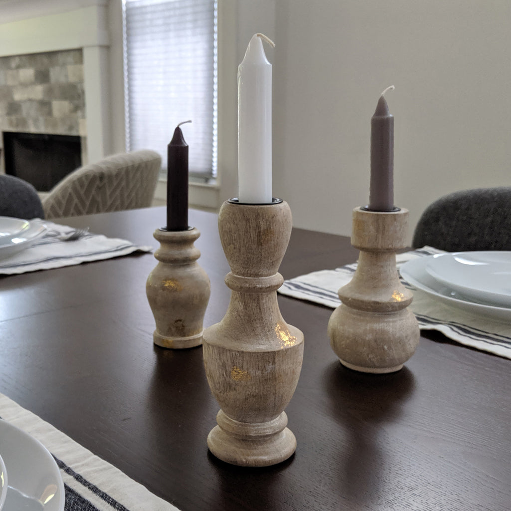 Image, white, grey and black candles in wooden candle holders, displayed on dining table.