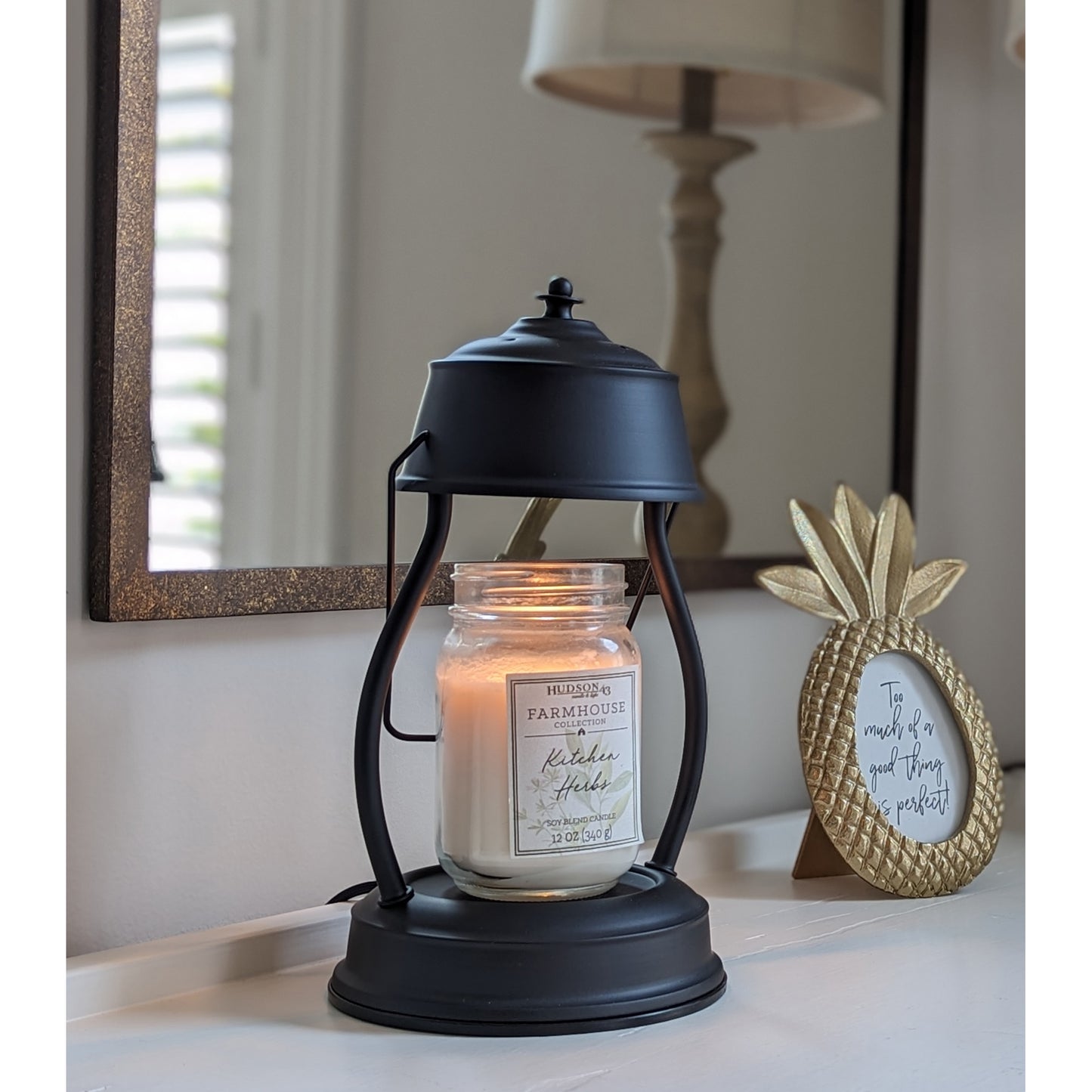 Image, lit black candle warmer with larger mason jar scented candle placed on an entry hall table.