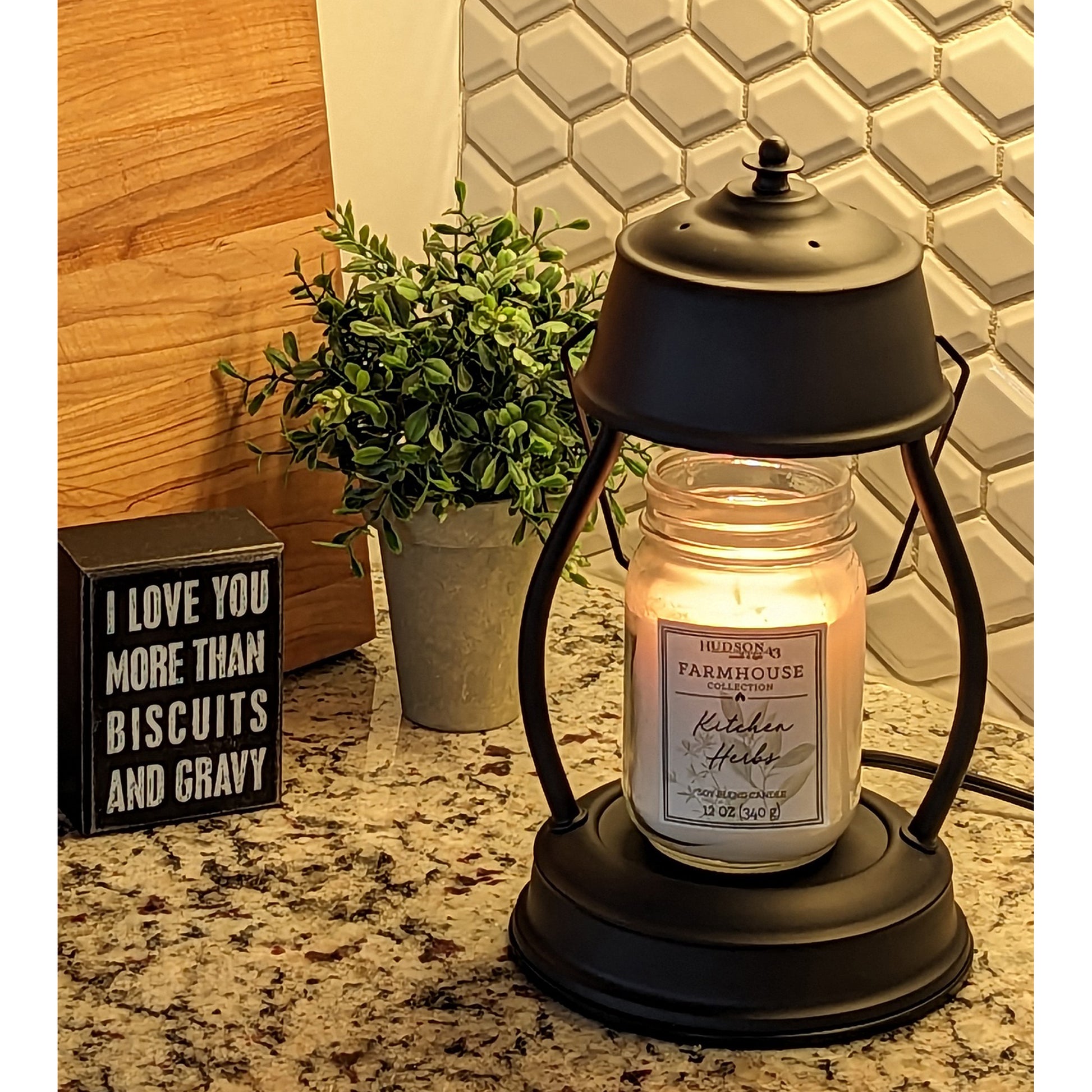 Image, lit black candle warmer on granite countertop in kitchen.