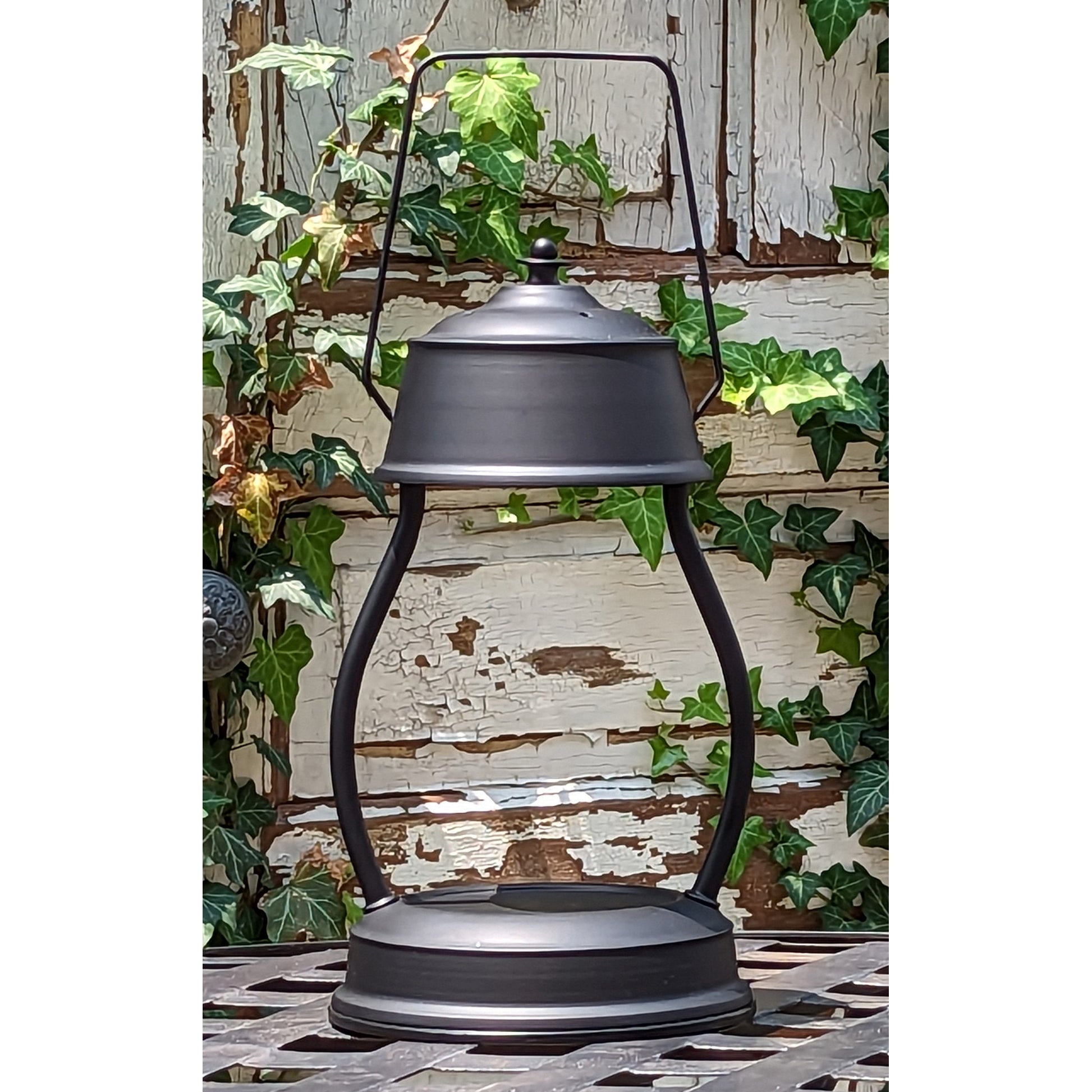 Image, black candle warmer on outdoor wrought iron table.