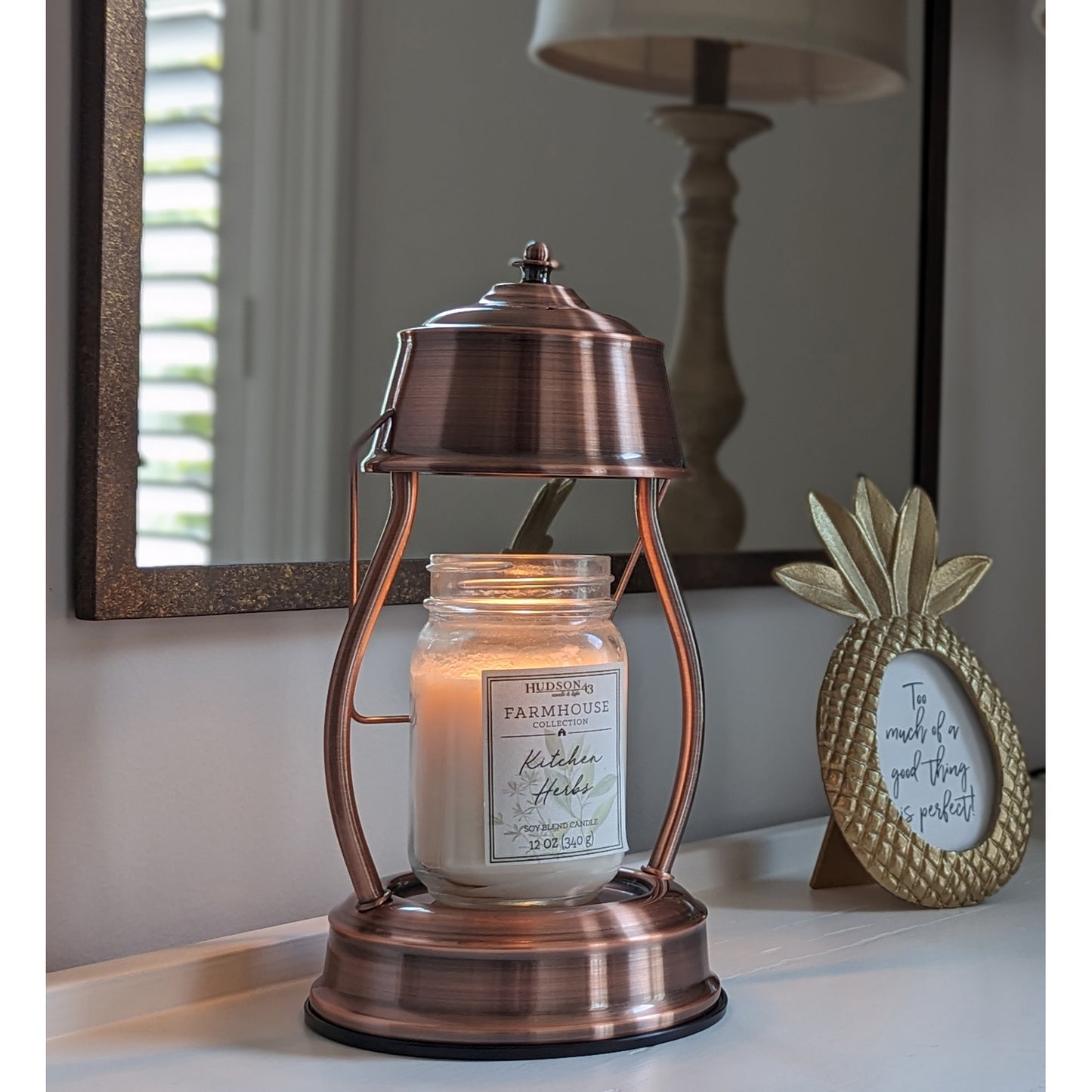 age, lit copper candle warmer with larger mason jar scented candle placed on an entry hall table.